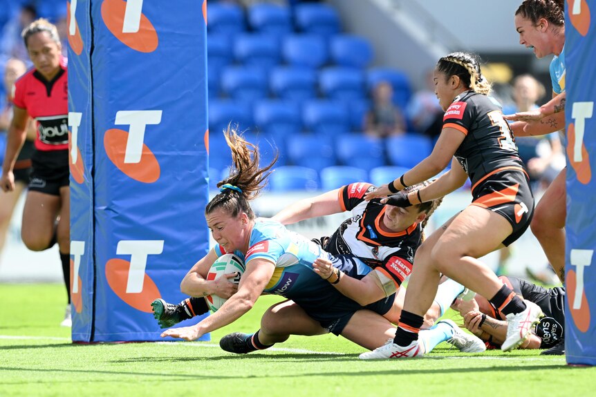 Georgia Hale dives over the line while Tigers players try to tackle her