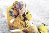 Ballandean rural firefighter Aaron Cox sitting on the ground with his head in his hands.