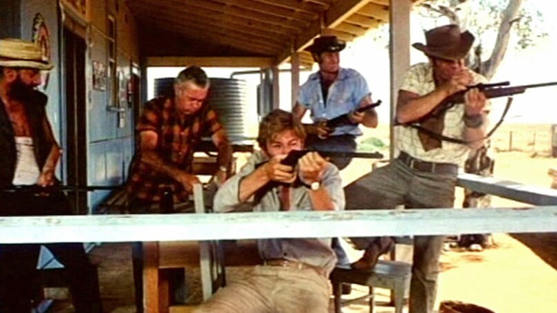 Men holding guns sit on the verandah of an outback home