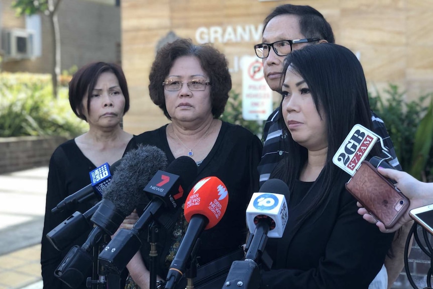 a family speaking in front of microphones, their faces solemn