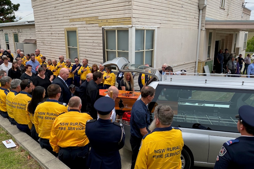 NSW Rural Firefighters form a guard of honour as a coffin is loaded into a hearse 