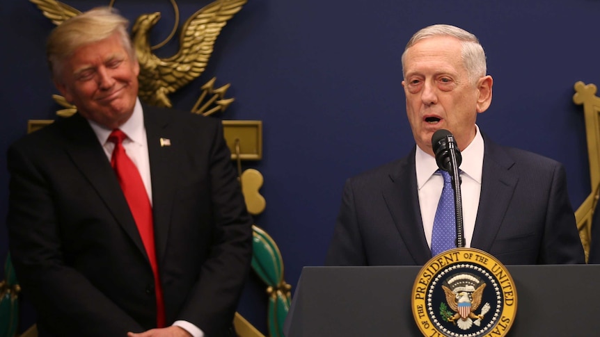 Donald Trump listens to remarks by Defence Secretary James Mattis, who stands at a podium.