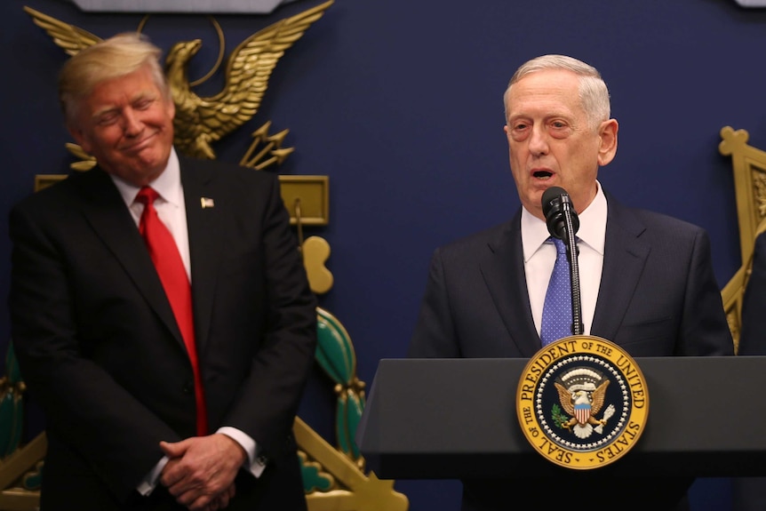 Donald Trump listens to remarks by Defence Secretary James Mattis, who stands at a podium.