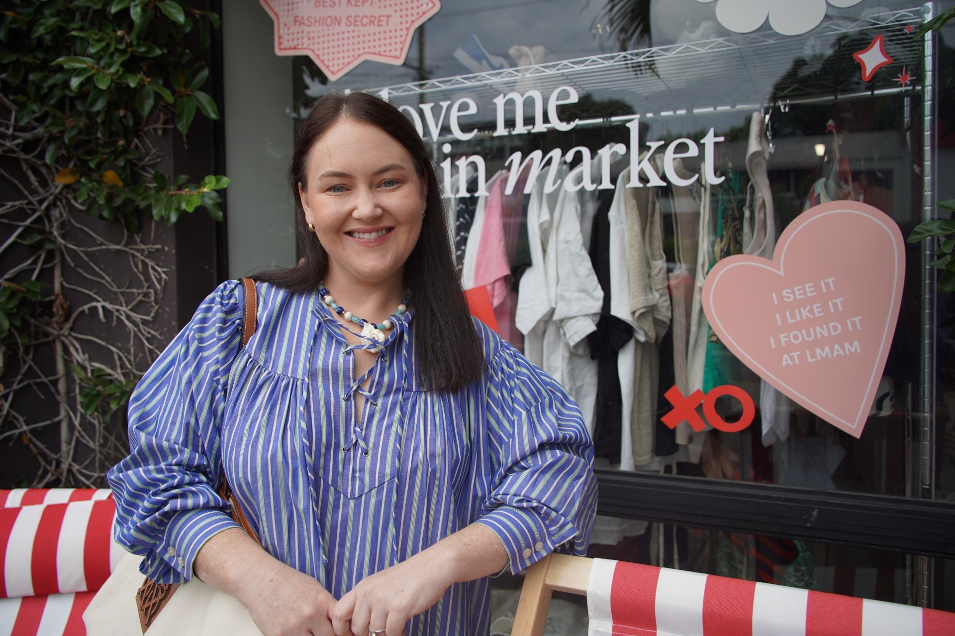 Una mujer con una camisa a rayas azules y blancas se encuentra frente al escaparate