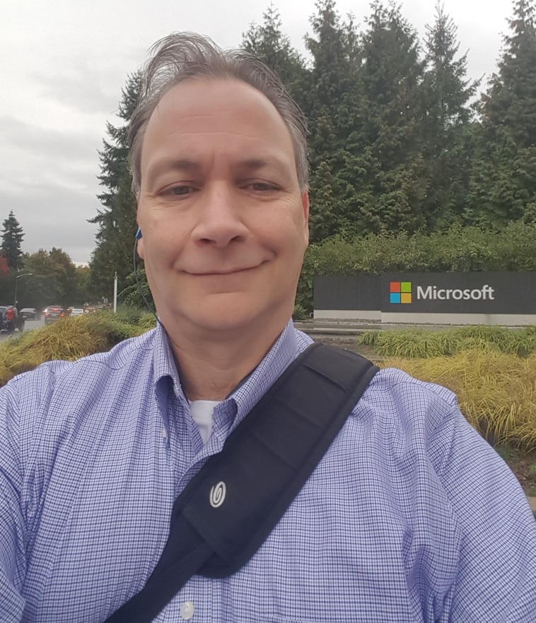 Un hombre se para frente a un cartel de Microsoft.