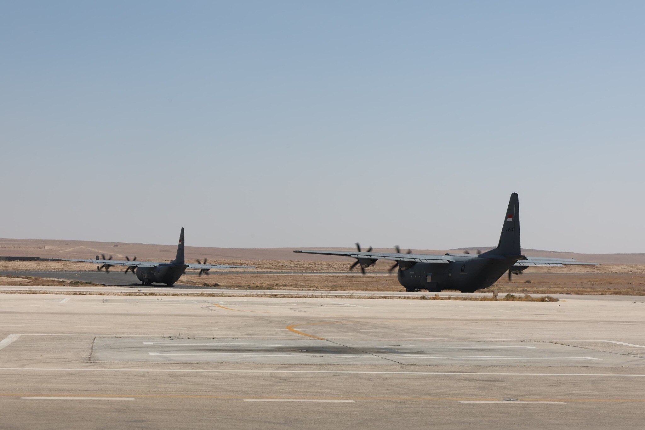 Two military planes taking off in an empty land.