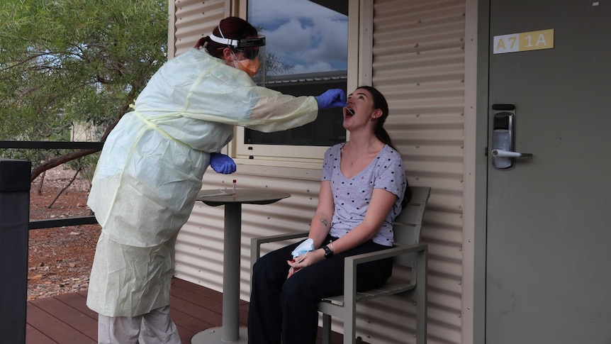 A health worker in full PPE does a COVID-19 test on a person at a quarantine facility near Darwin.