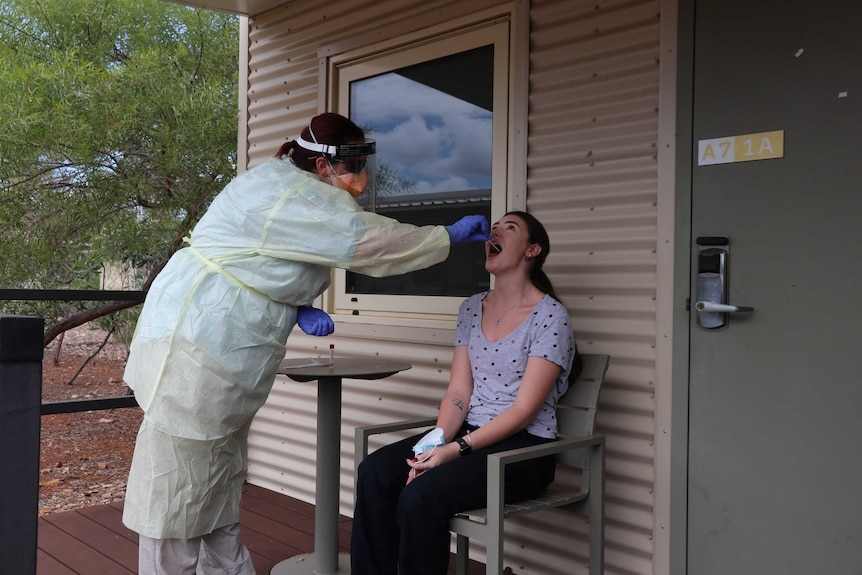 A health worker in full PPE does a COVID-19 test on a person at a quarantine facility near Darwin.