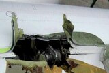 A man looks at the damage done to the wing on the Qantas A380 jet after an engine exploded
