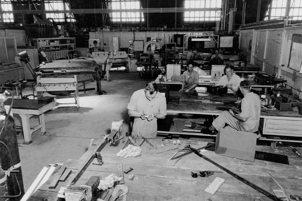 Black and white photo of men working in an old workshop.