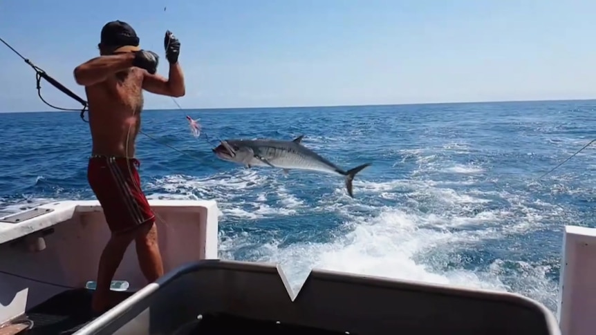 Photo of a man fishing off a boat in the ocean.