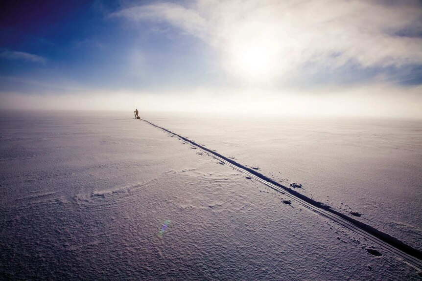 A long trail stretches through the snow, as a lone explorer heads towards the South Pole.