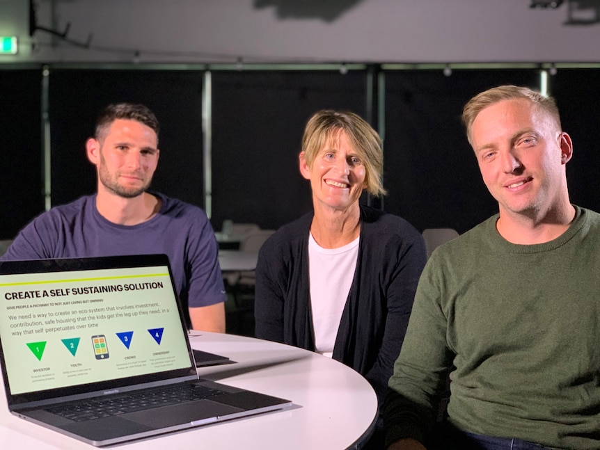 A woman sits between two men with a laptop computer in the foreground