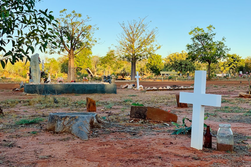 A white cross marks a grave in an outback cemetery.