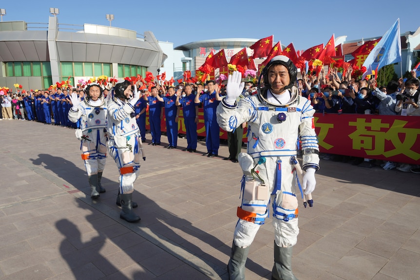 Chinese astronauts wave goodbye during a sendoff ceremony