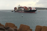 Tug boats escort a container ship into Port Botany.