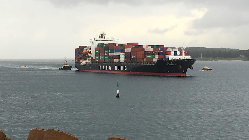 Tug boats escort a container ship into Port Botany.