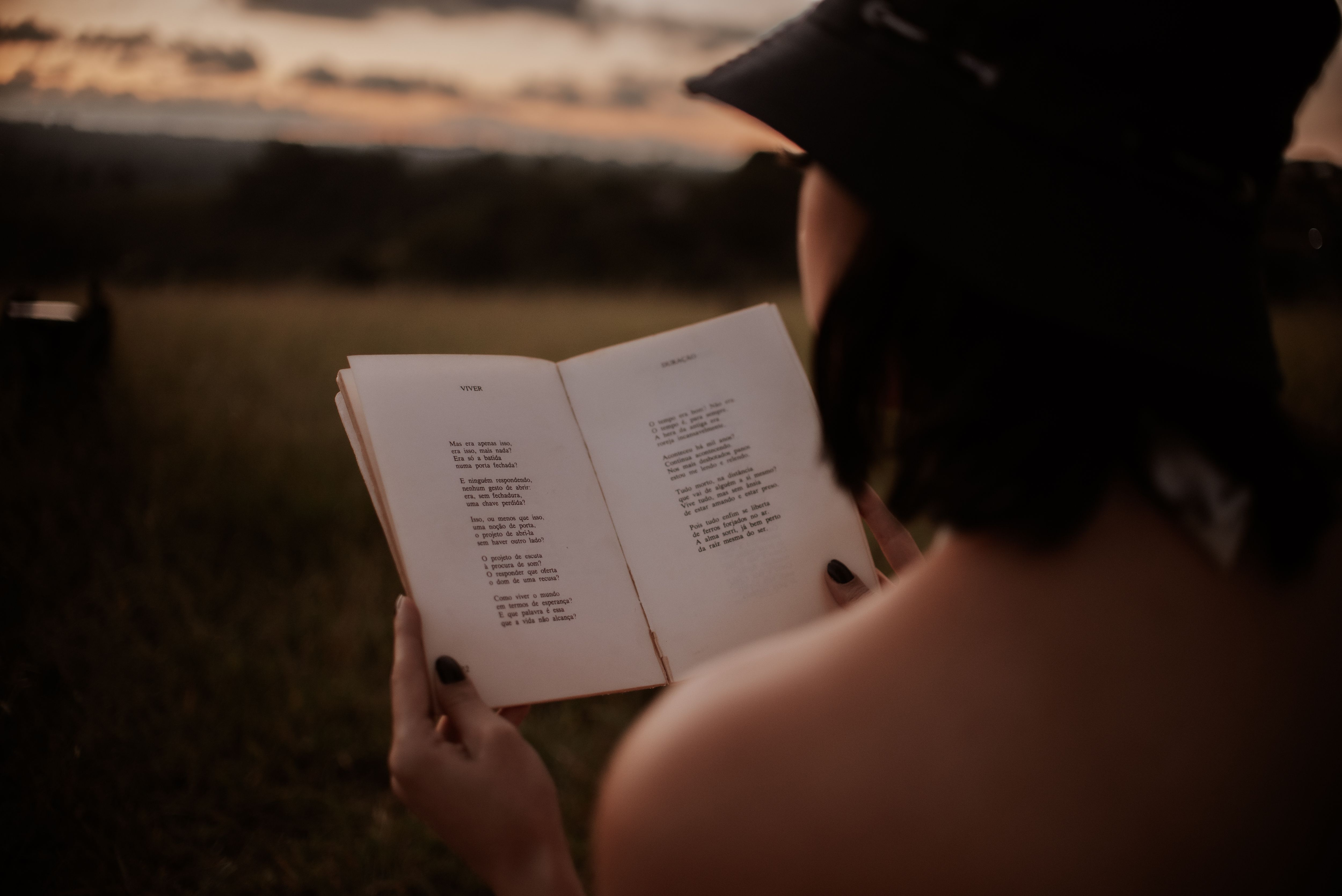 A woman reads a book of poetry in a field