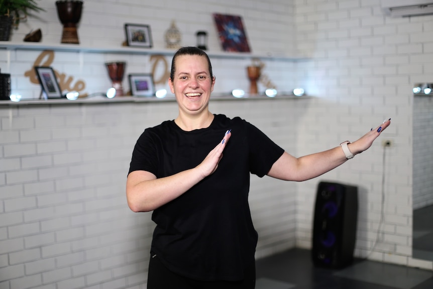 A woman smiles while doing a salsa pose 