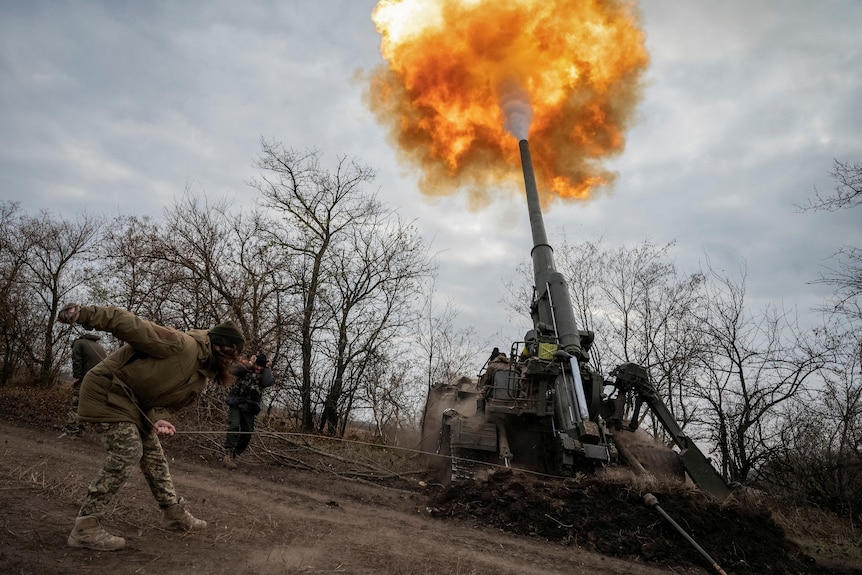 A soldier fires an artillery piece, creating a spectacular burst of flame.