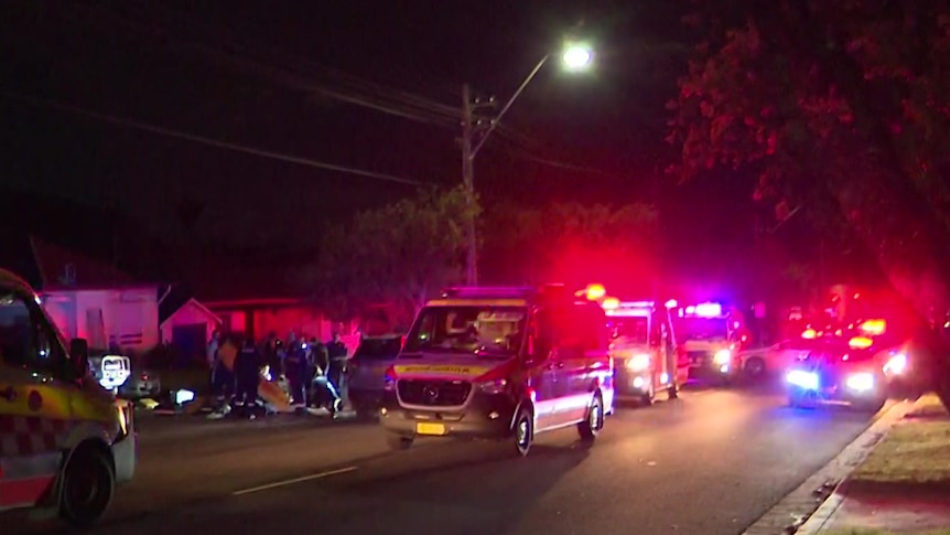 Night time scene of ambulances and police cars in a suburban street. 