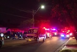 Night time scene of ambulances and police cars in a suburban street. 