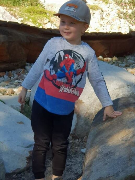 Boy in Spider-Man shirt standing on rocks