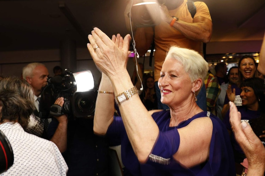 A woman clapping in front of supporters