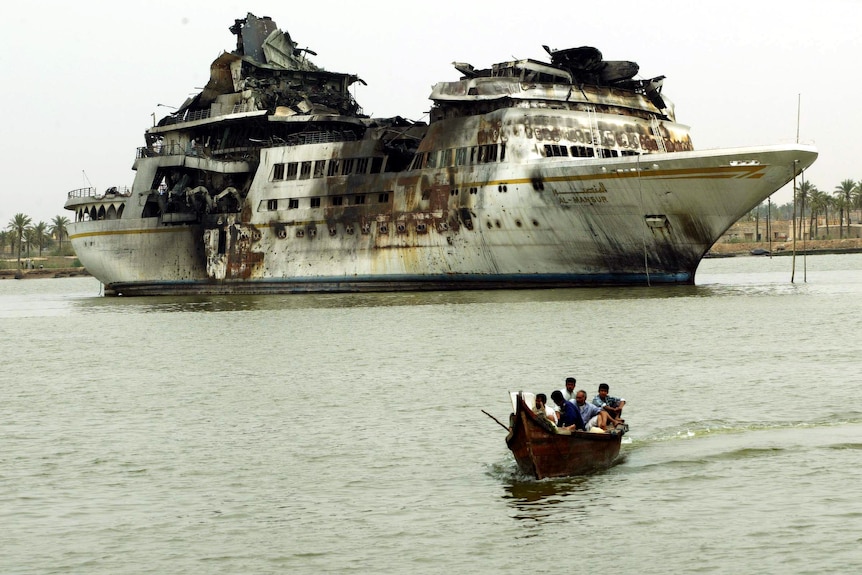 A destroyed yacht with a small kayak in the foreground