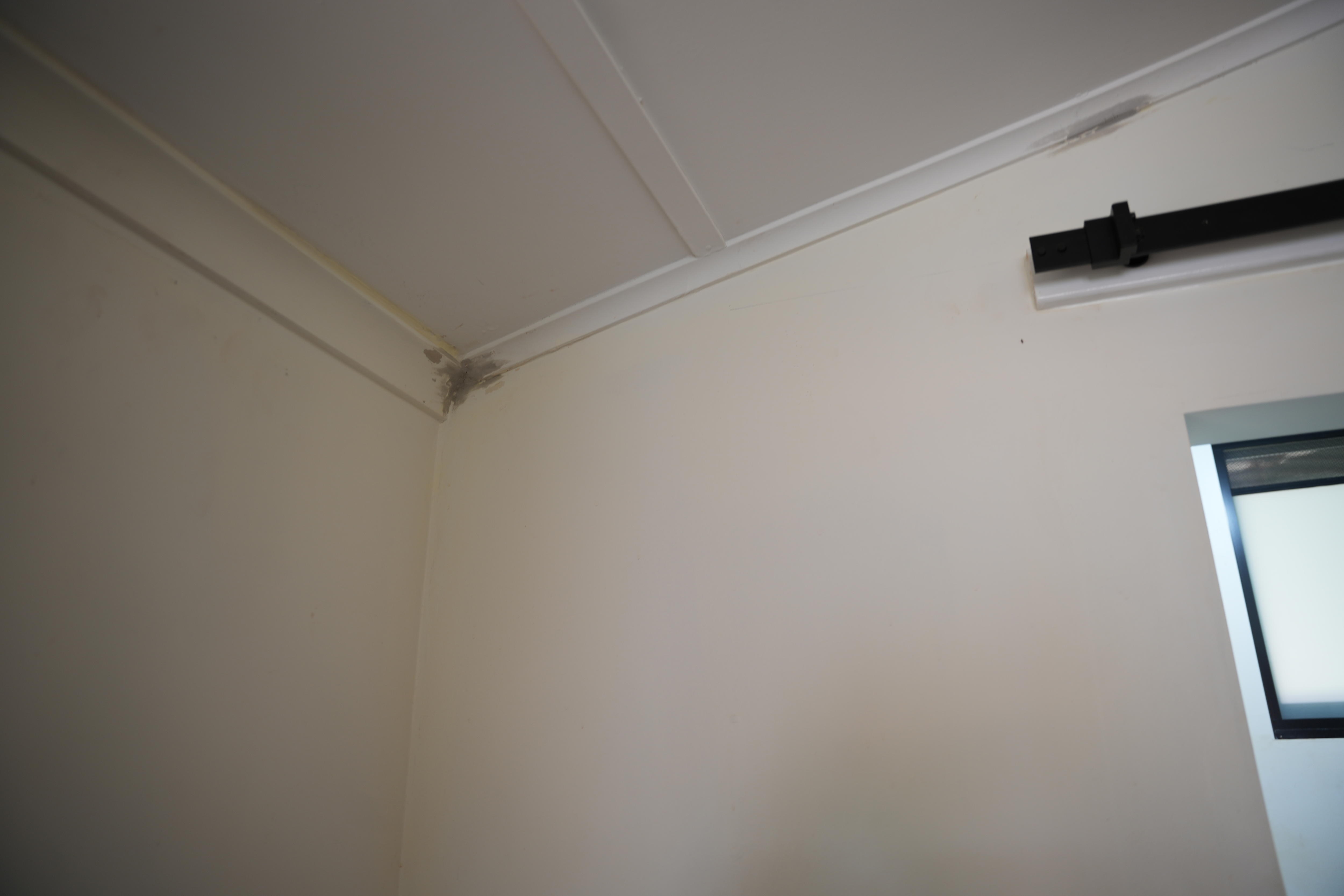 una pared con manchas grises en la parte superior y en la esquina.
