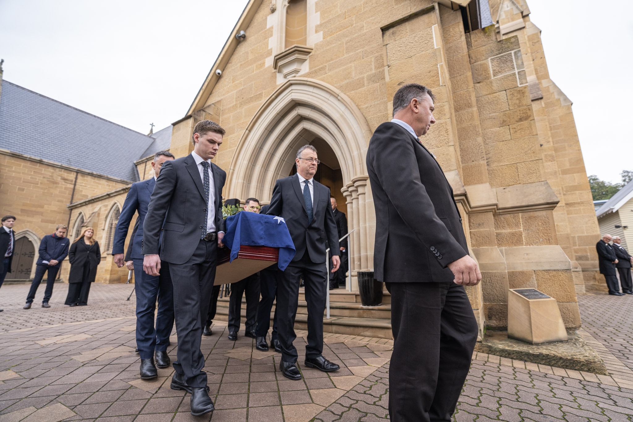 Pall bearers carry Michael Tate's coffin, draped in an Australian flag, outside St Mary's Cathedral.
