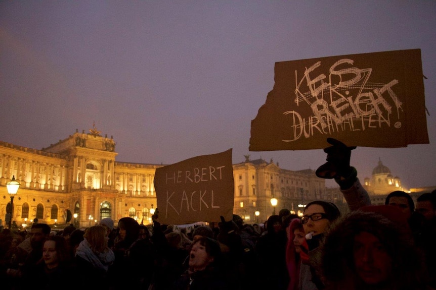 A protester holds a placard reading 'Enough Already', another makes a play on Interior Minster Herbert Kickl's surname.