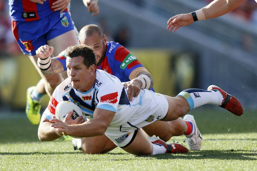 Greg Bird of the Gold Coast Titans dives through the Newcastle Knights defence 