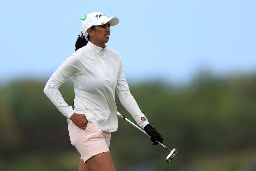 Aditi Ashok grimace alors que le vent souffle sur elle en tenant son club de golf dans sa main gauche