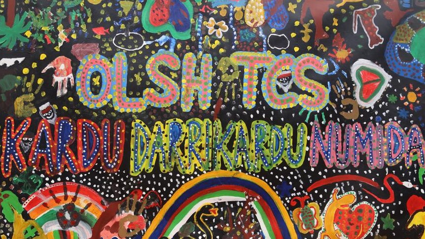 A colourful wall painted with words and traditional Indigenous dot style.