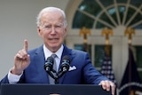 Joe Biden speaking at a lectern with one finger pointed in the air.