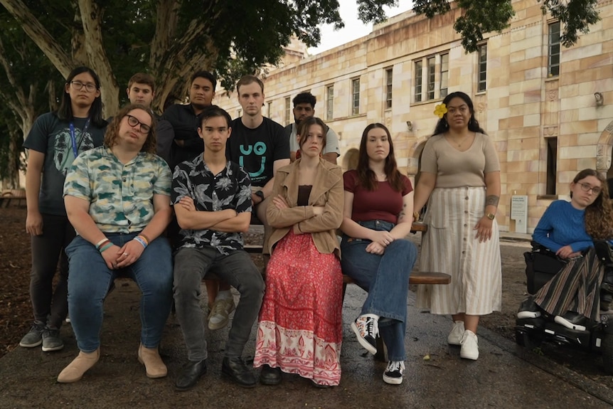 Eleven students, women and men, sit in a group looking at the camera.