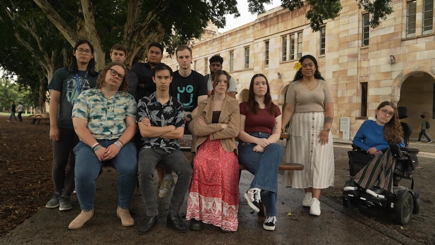 Eleven students, women and men, sit in a group looking at the camera.