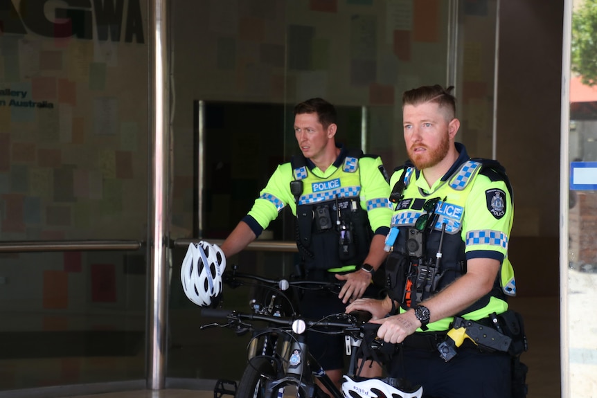 Uniformed police officers pictured wheeling bikes out of the building. 