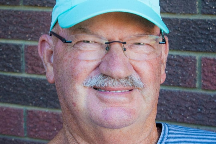 Deon Hewitt wearing glasses and a blue cap and smiling