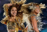 Two women with flowing hair smiling and performing on stage