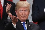 Donald Trump gestures and shrugs at a podium
