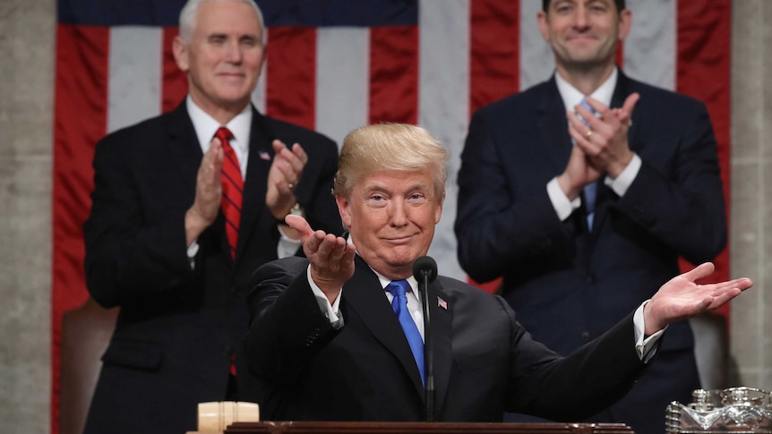 Donald Trump gestures and shrugs at a podium
