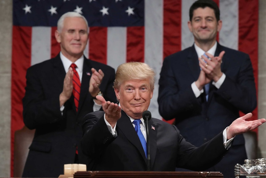 Donald Trump gestures and shrugs at a podium