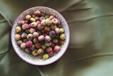 An aerial view of round, multi-coloured (pink, green and yellow) berries in a bowl.