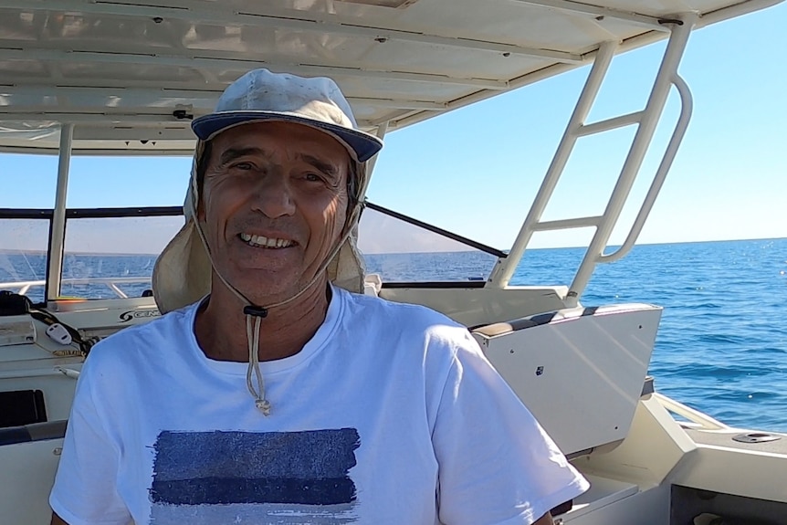 Portrait of man on a boat with hat, smiling to camera