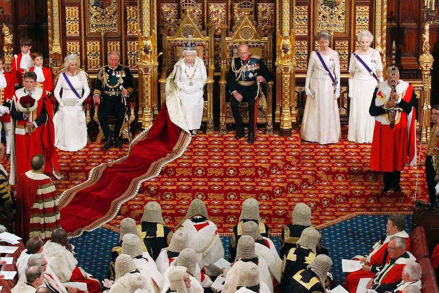 The Queen and Prince Philip sitting beside each other in Parliament, looking out into the crowd.