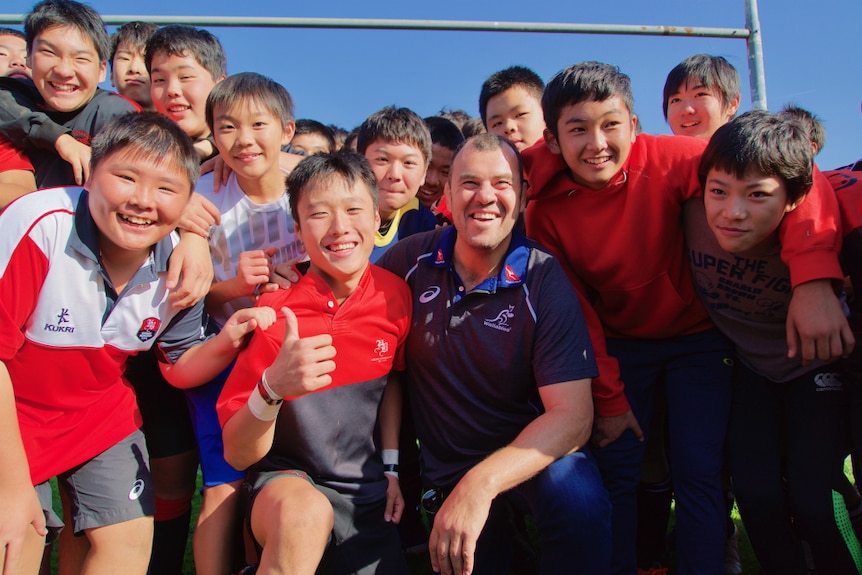 Michael Cheika smiling with young rugby players in Hokkaido.