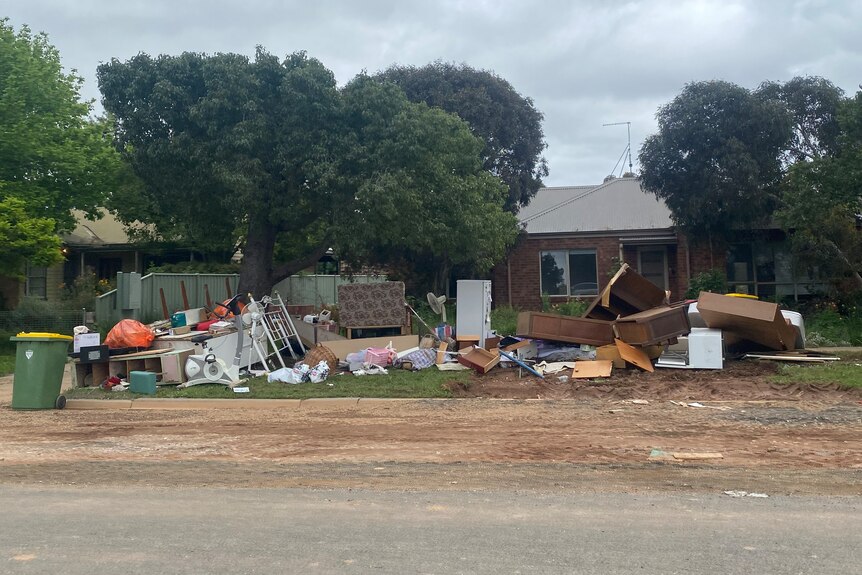 Furniture and damaged items stacked outside a house following a flood.