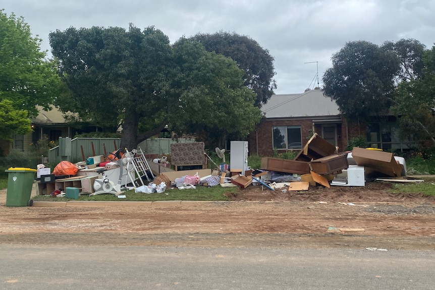 Furniture and damaged items stacked outside a house following a flood.